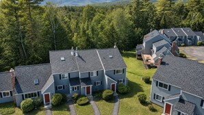 A residential area with multiple two-story houses, each with a distinct architectural style featuring gabled roofs and a mix of brick and siding exteriors.