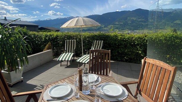 An outdoor dining area with a table set for four, surrounded by wooden chairs, overlooking a mountainous landscape. - Gemütliches Haus mit 2 Schlafzimmern im Zentrum von Kaprun mit Schönen Terrassen (Kaprun)