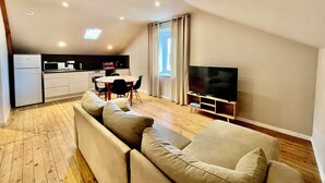 Un apartamento moderno con comedor, kitchenette y sala de estar con sofá y televisor.