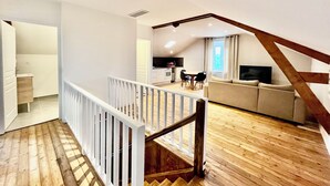 Amplia sala de estar con una escalera de madera, un sofá y una mesa de comedor.