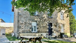 Un edificio rústico de piedra con una mesa y bancos de madera en el patio.
