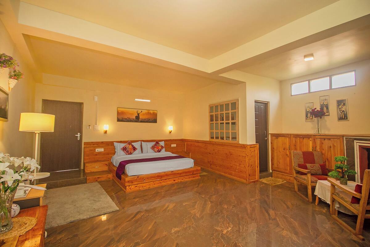 Un dormitorio amplio con una cama de madera, una mesita de noche, una lámpara y una pequeña mesa con un florero.