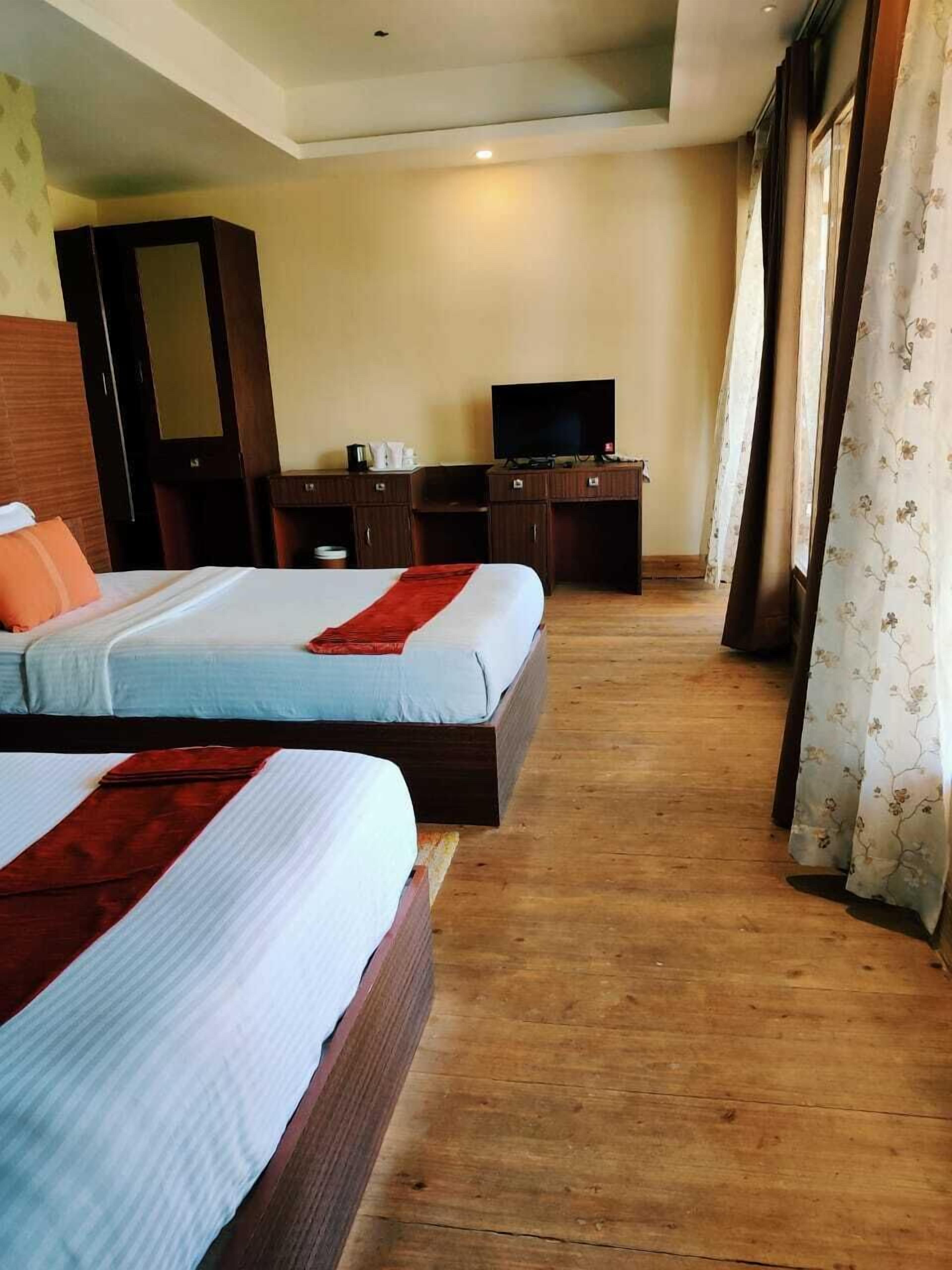 Habitación de hotel con dos camas, televisión, armario y escritorio.