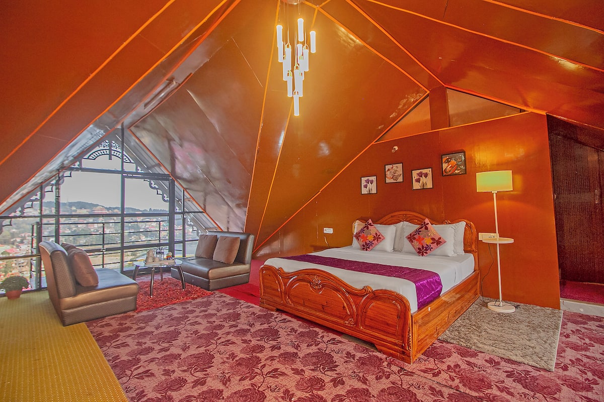 Un dormitorio con una cama grande, un sofá, una mesita y una lámpara.