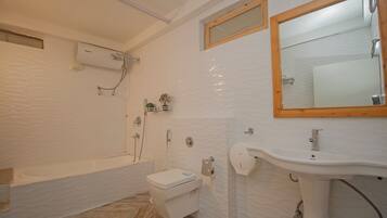 A bathroom with a bathtub, toilet, sink, and a mirror.