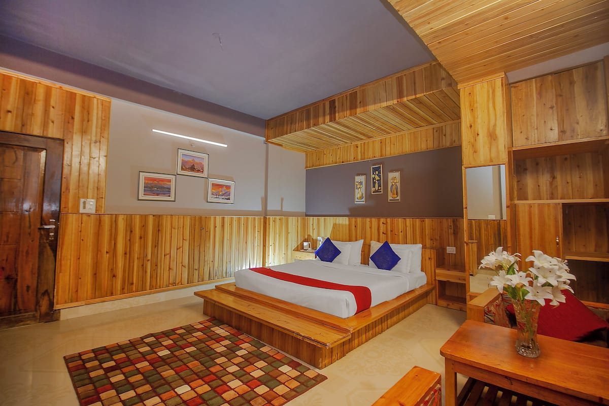 Un dormitorio con decoración de madera, una cama, mesitas de noche y una mesilla.
