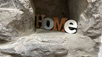 Eine Steinmauer, auf der das Wort „HOME“ mit Holzlettern steht.