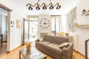 A living room with a sofa, a table with papers, a wall clock, and a decorative wall. - Dream Vacation (Argegno)