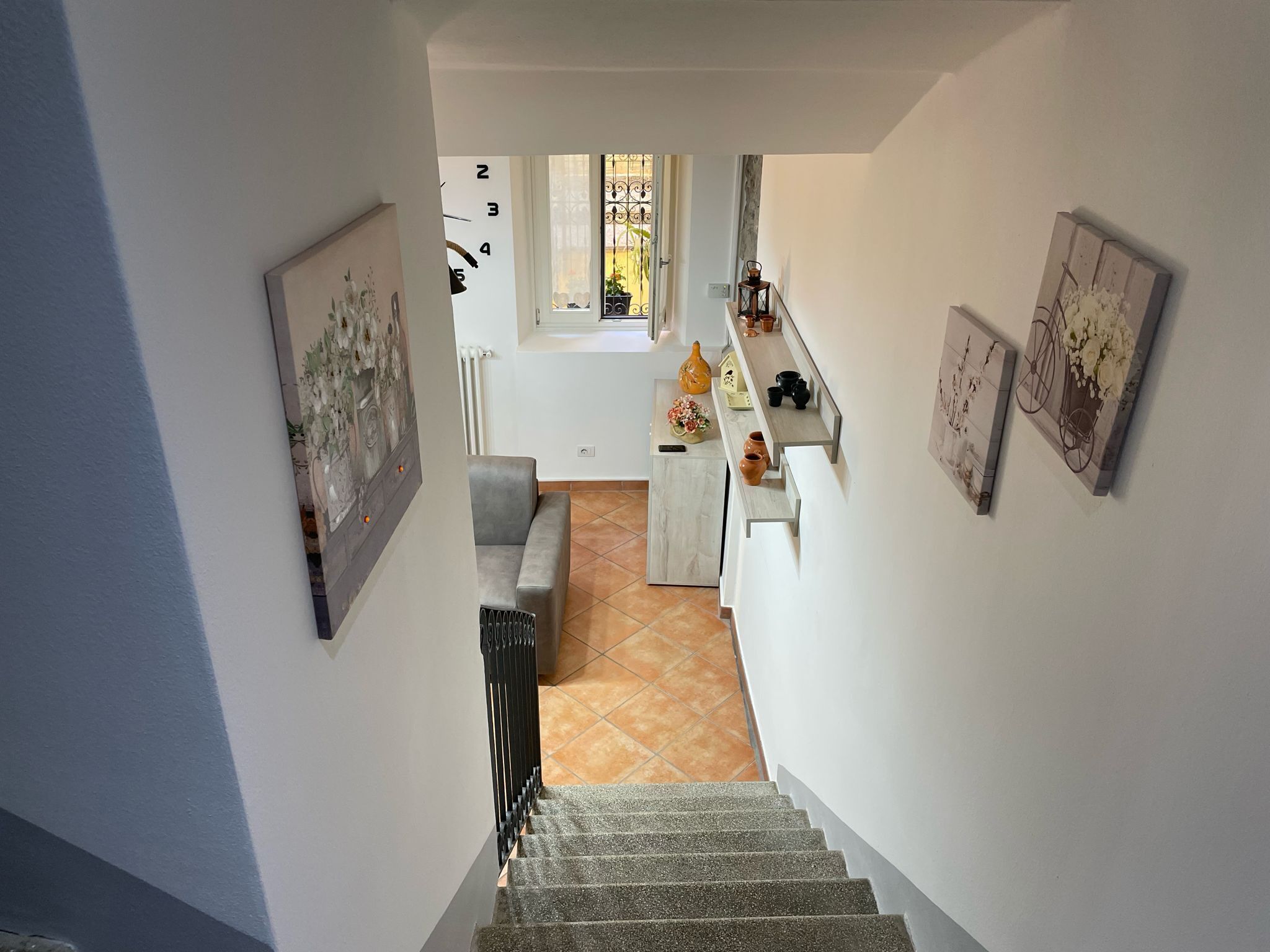 A staircase leading to a living area with a sofa, a small table with decorative items, and a window with a view of the outside.