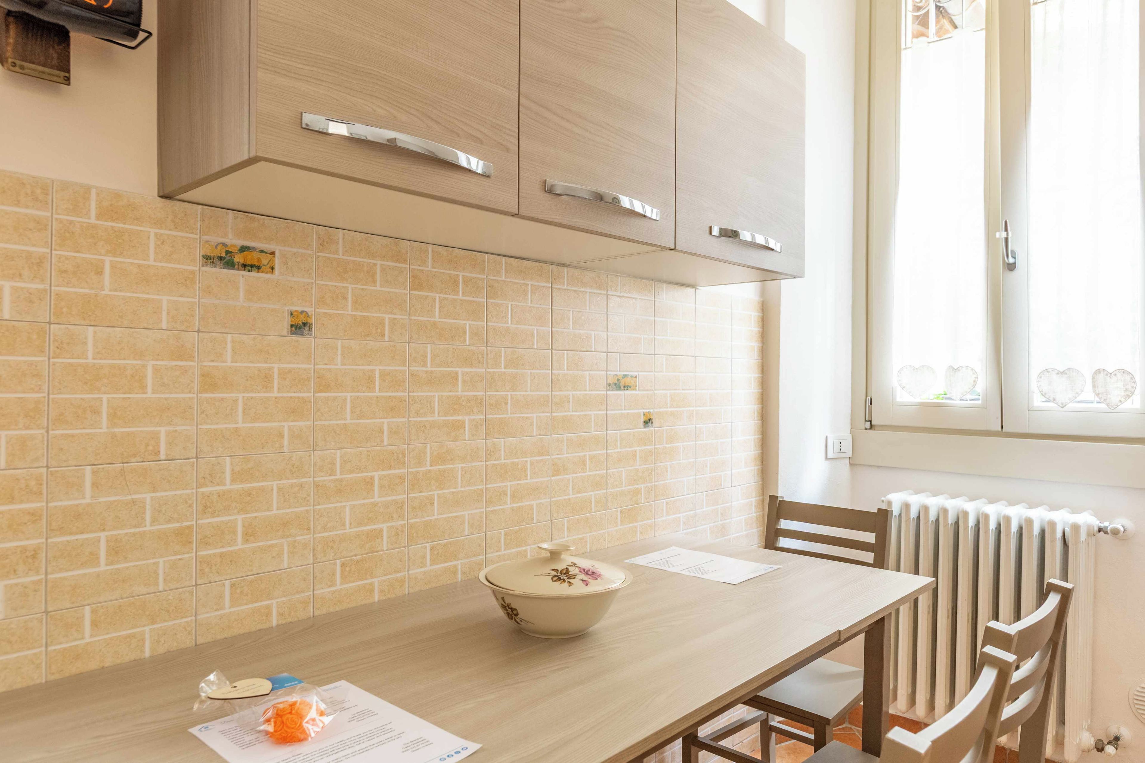 Una cocina con una mesa de madera, un bol y una ventana con cortinas.