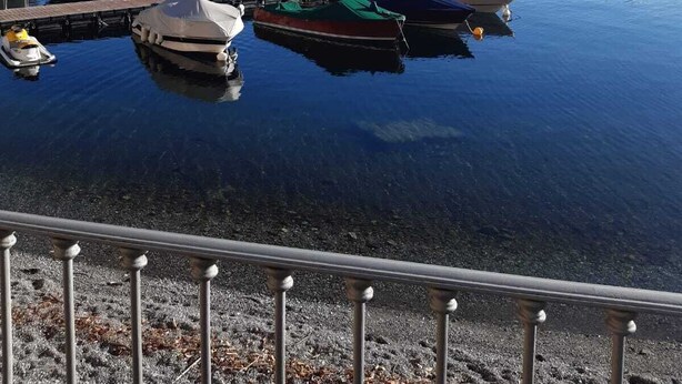 A marina with boats docked, calm water, and mountains in the background. - Dream Holiday  (Argegno)