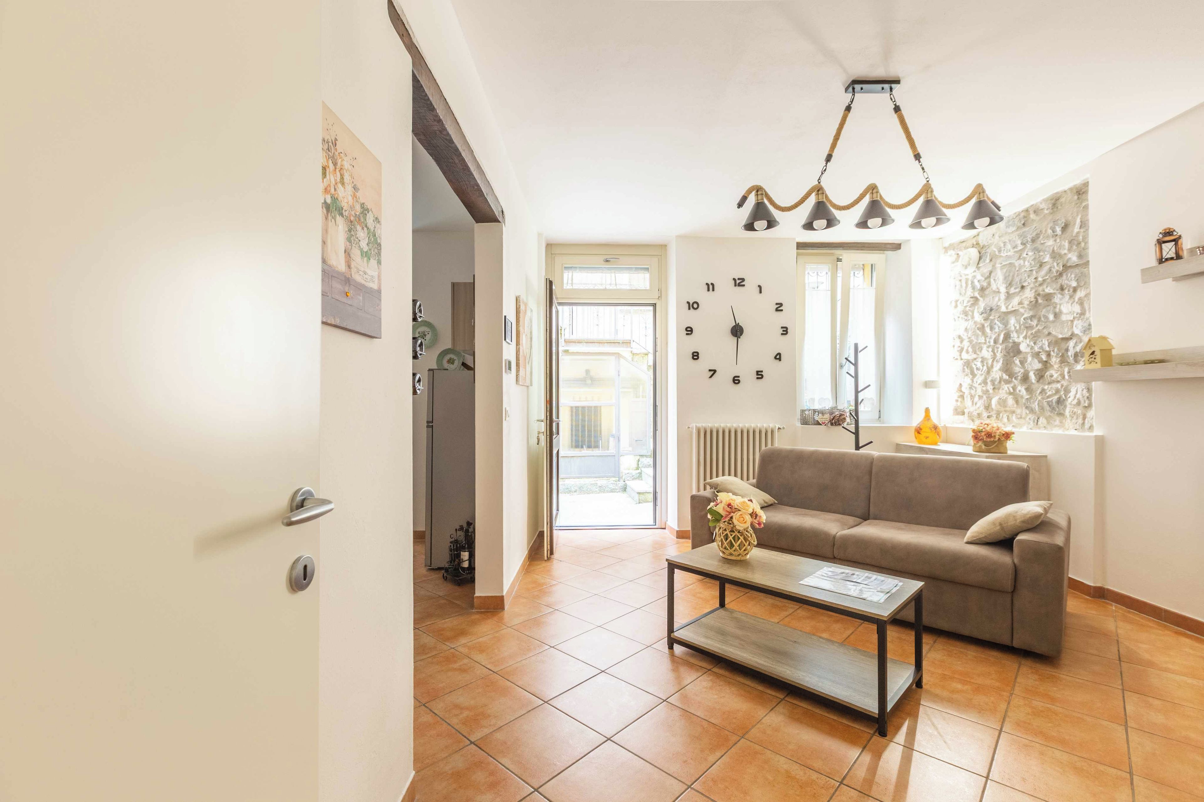 Un salon comprenant un canapé, une table basse, une horloge murale et un luminaire suspendu.