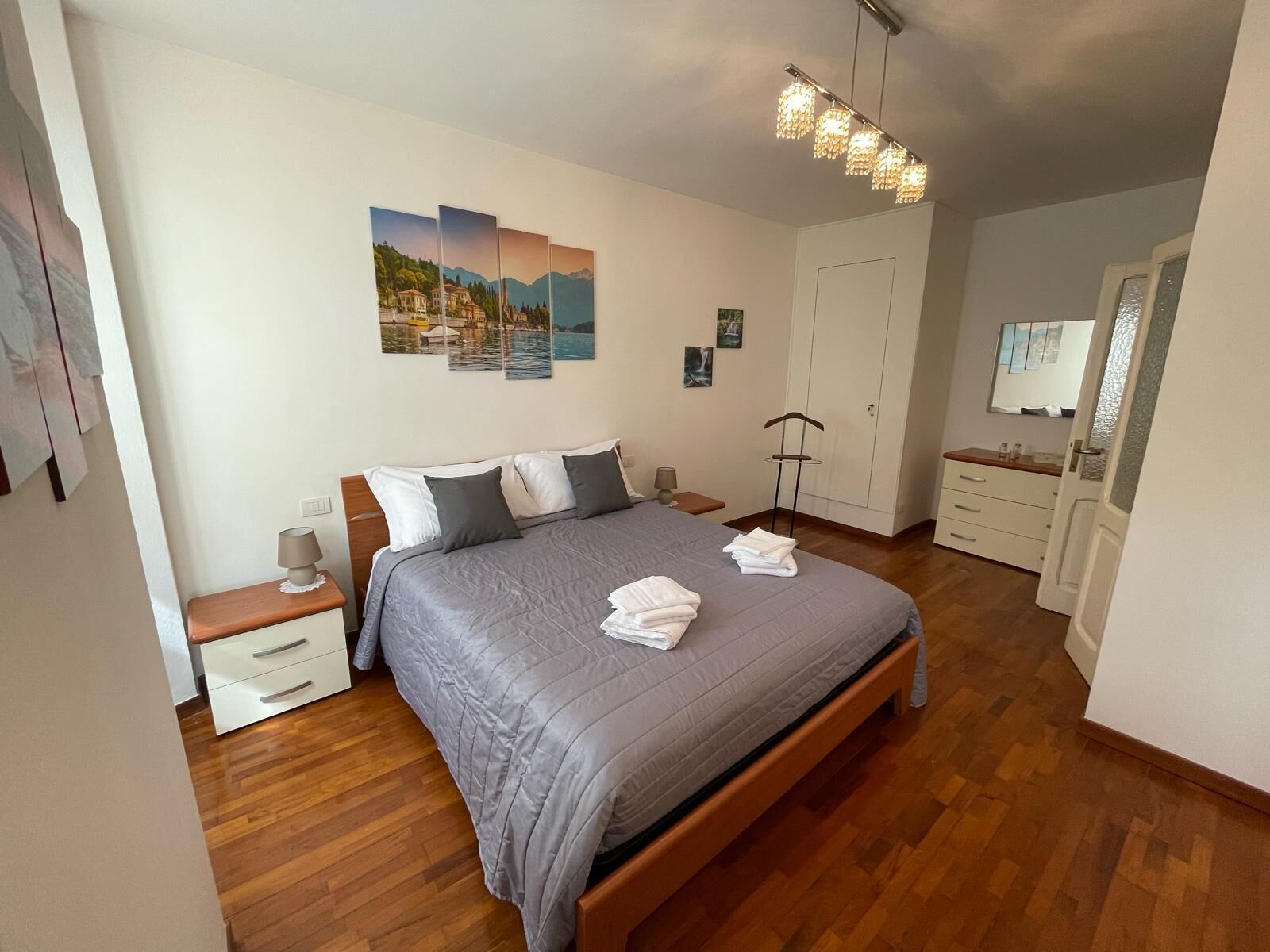 A neatly arranged bedroom with a bed, bedside tables, a wardrobe, and a hanging light fixture.