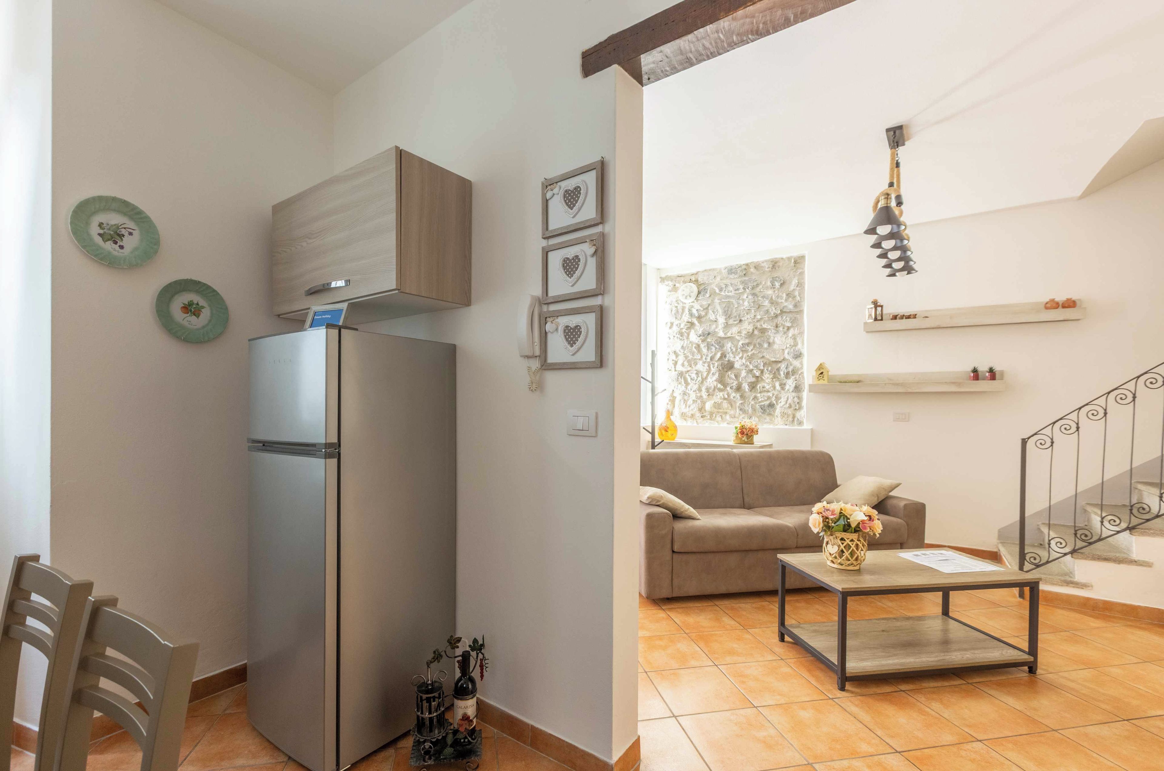 A modern kitchen with a built-in refrigerator, a dining area with a chair, and a living room with a sofa and a coffee table.