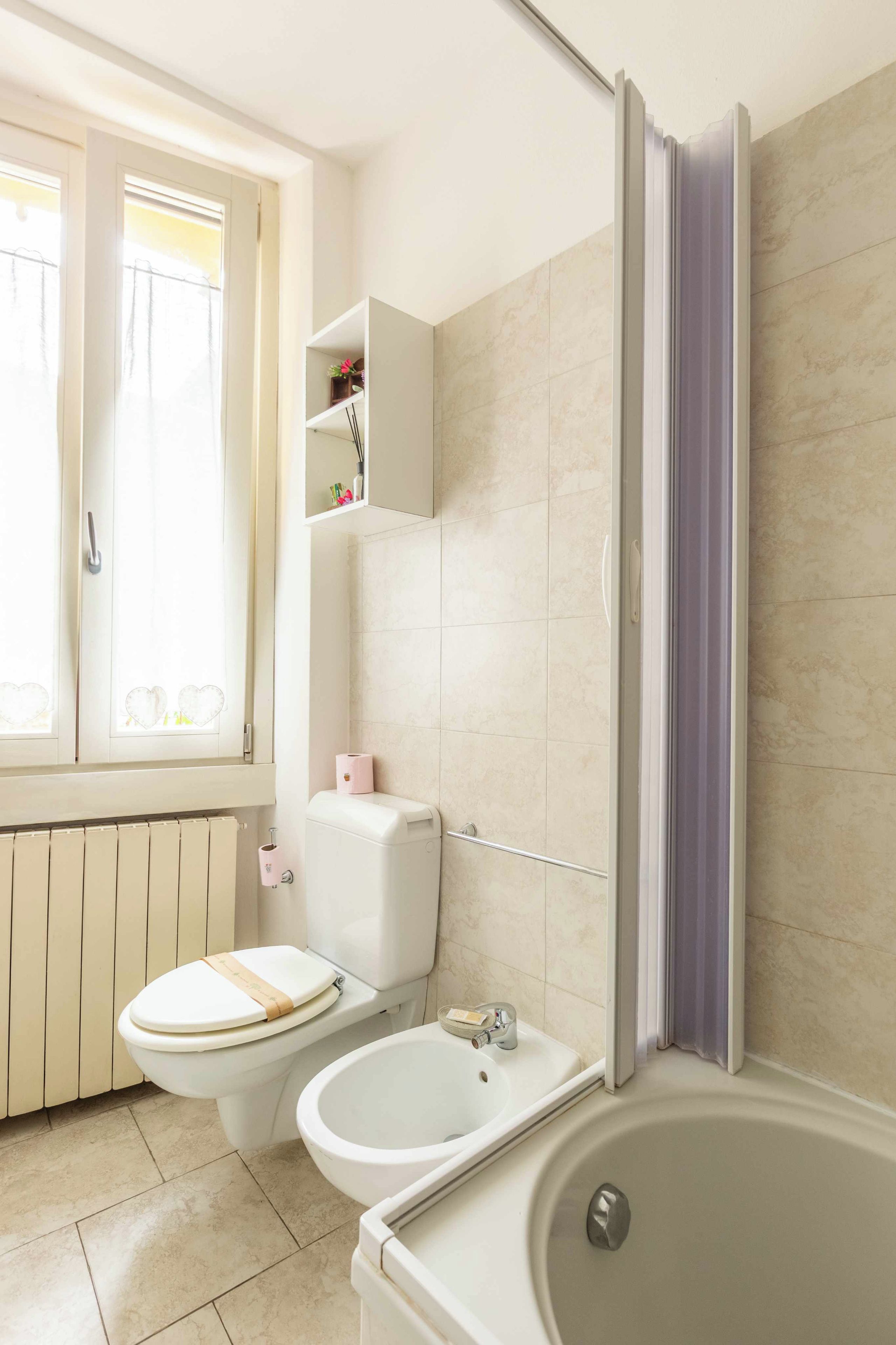 Een badkamer met toilet, bidet en bad.