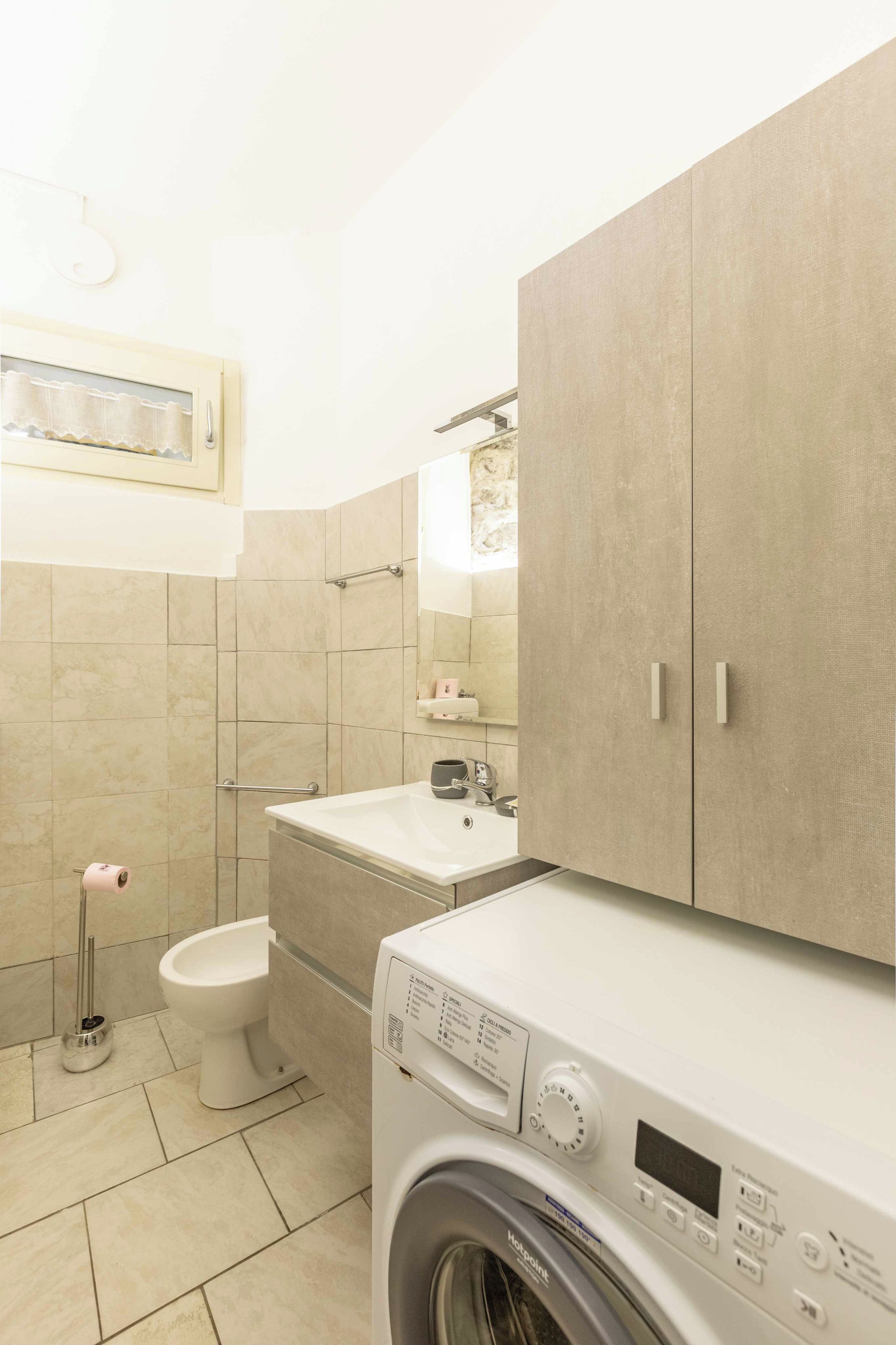 A modern bathroom with a toilet, sink, and washing machine.