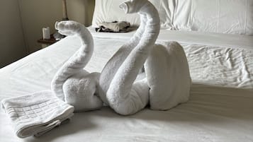 Un lit avec du linge de lit blanc et deux serviettes en forme de cygne.