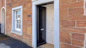 A brick building with a white-framed window and a black door.