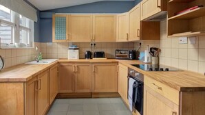 A kitchen with wooden cabinets, a tiled backsplash, a sink, a stove, and a toaster.