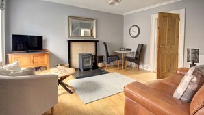 A living room with a fireplace, a television, a sofa, and a dining area.