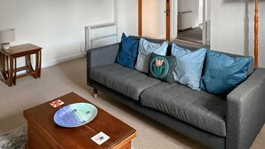 A living room with a grey sofa, wooden coffee table, and a small wooden side table. - A quirky 2-bedroom town house just out of the centre of Tain. (Tain)