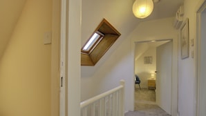 Un couloir étroit avec un plafond en pente et une lucarne.