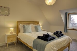 Un lit bien fait, avec des oreillers et une couverture, une lampe de chevet et une fenêtre avec des rideaux.