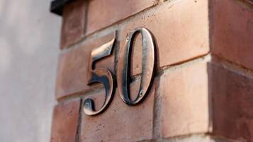 Primer plano del número '50' de metal sujeto a una pared de ladrillo.
