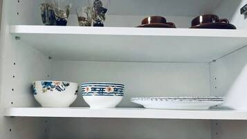 A kitchen shelf with various items including bowls, mugs, and jars.