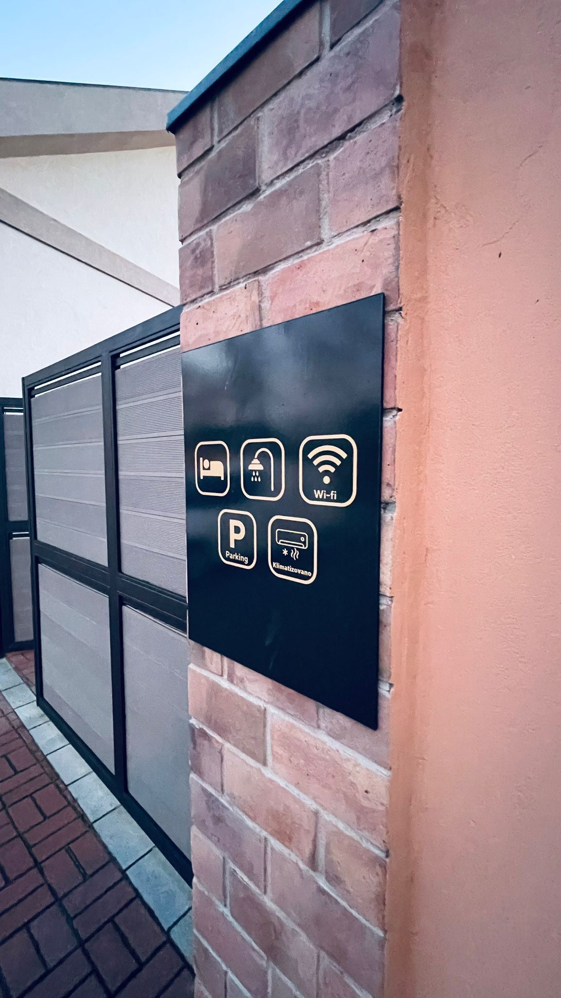 Un senyal negre amb icones que indiquen serveis com Wi-Fi, aparcament i zones amb climatització.