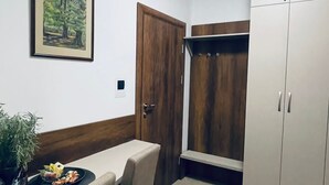 Una habitación pequeña y luminosa con una mesa de comedor, sillas, un cuadro en la pared, una puerta de madera y un armario.