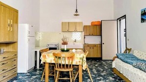 Una cocina compacta con mesa y sillas, un refrigerador y una estufa.