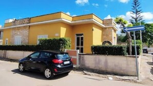 Un edificio amarillo con un coche negro estacionado adelante.