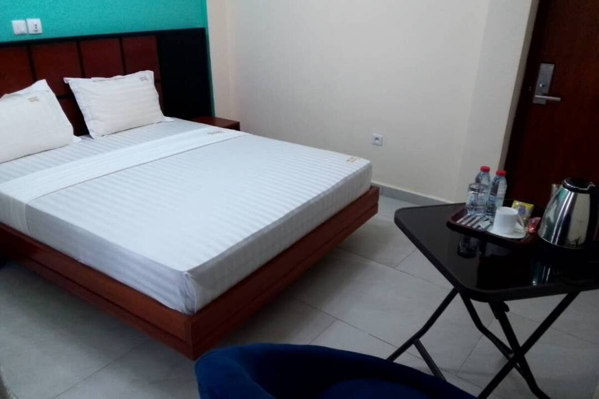 A hotel room with a bed, a small table with toiletries, and a blue chair.