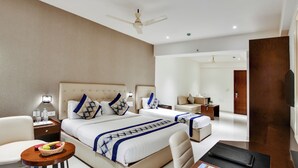 A modern hotel room with two beds, a sitting area, and a TV. - AM Hotel Kollection: Manasa Inn, Tirupati (Tirupati)