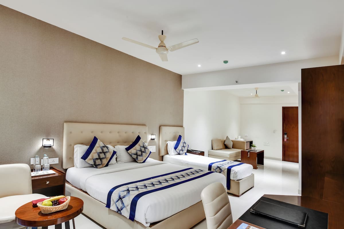 Una habitación de hotel moderna con dos camas, una zona de estar y un televisor.