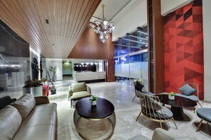 A modern lobby with a wooden ceiling, a chandelier, a reception desk, and a seating area with a round table and chairs. - AM Hotel Kollection: Manasa Inn, Tirupati (Tirupati)