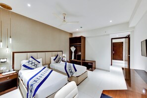 A hotel room with two beds, a ceiling fan, bedside tables, a TV, and a wardrobe. - AM Hotel Kollection: Manasa Inn, Tirupati (Tirupati)