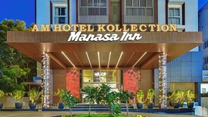 The exterior of the Am Hotel Kollection Manasa Inn, featuring a modern facade with a prominent entrance, illuminated signage, and landscaped surroundings. - AM Hotel Kollection: Manasa Inn, Tirupati (Tirupati)