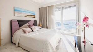 Un dormitorio moderno con una cama grande, vistas a la ciudad y un cuadro en la pared.