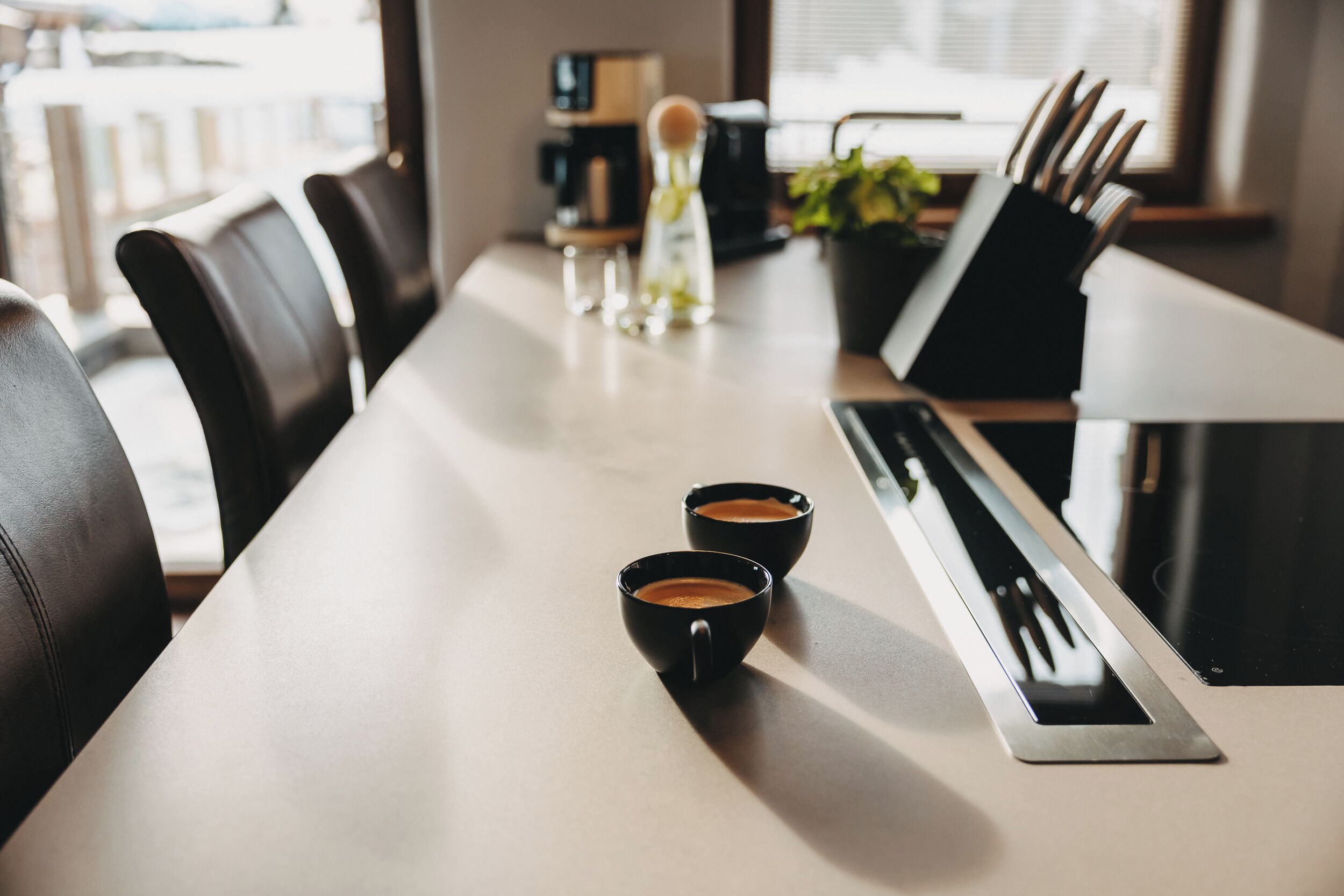 Ein Konferenztisch mit zwei schwarzen Kaffeetassen, einem Messerblock und einer Wasserflasche.