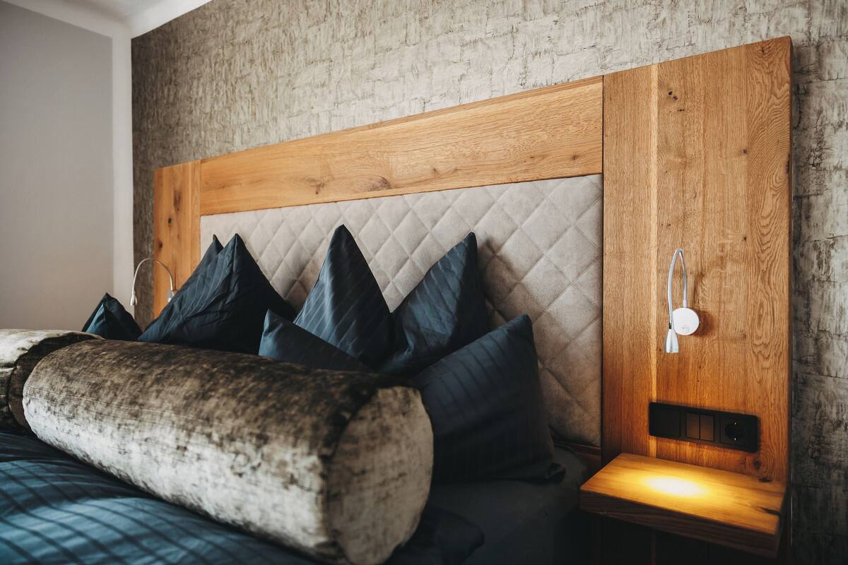 A bed with a quilted headboard, multiple pillows, and a bedside table with a nightstand.