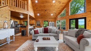 A wooden cabin interior with a living area, kitchen, and large windows. - Tranquil Ridge- View, pet friendly, hot tub, sauna (Epworth)