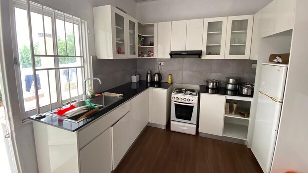 Una cocina moderna con armarios blancos, encimera negra, estufa y lavabo.