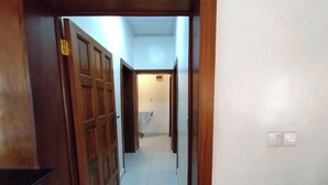 Un pasillo con puertas de madera y suelo de baldosas.