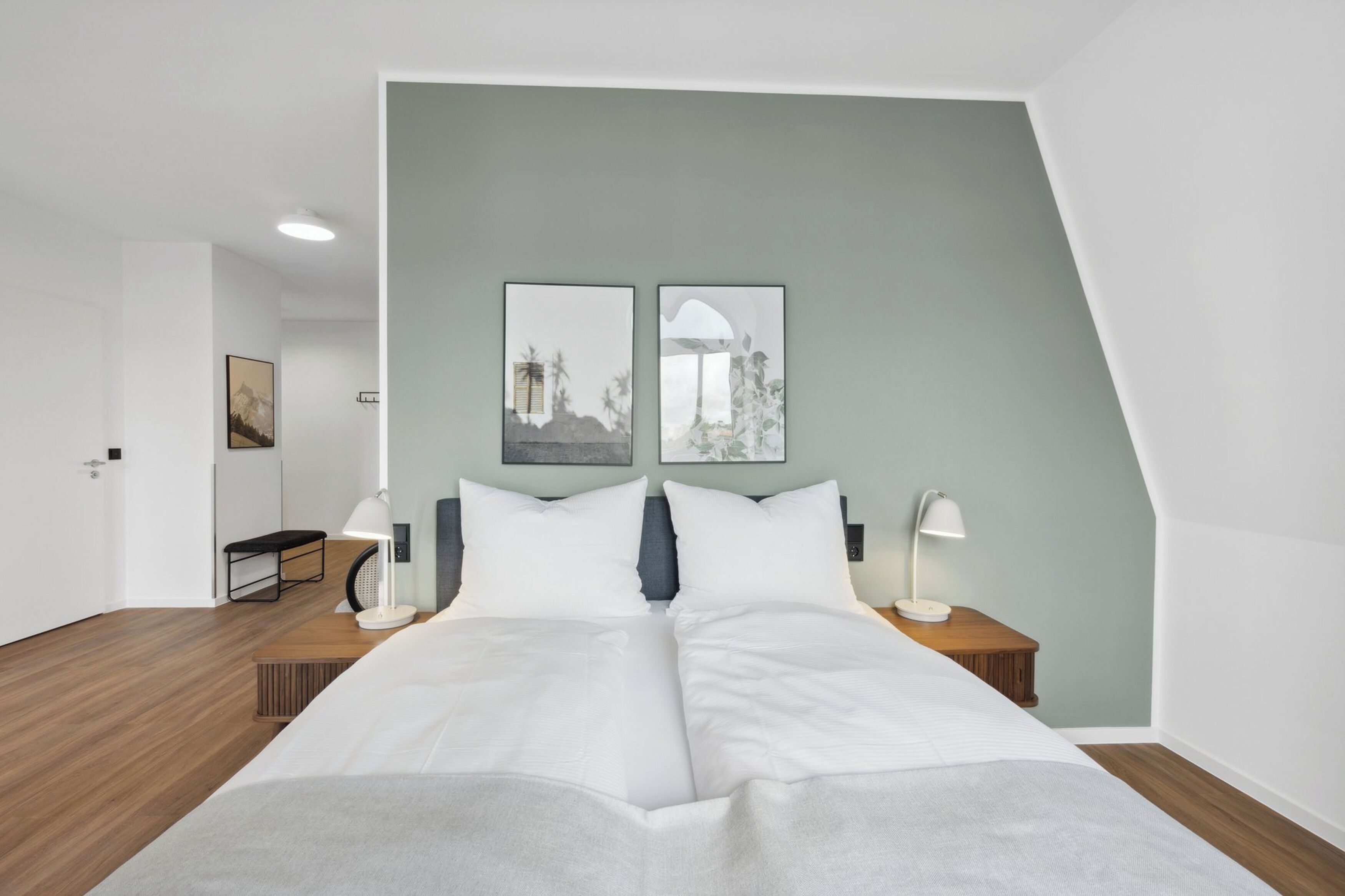 A modern bedroom with a bed, bedside tables, and artwork on the wall.