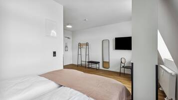 A modern bedroom with a bed, a desk, a chair, and a large mirror.