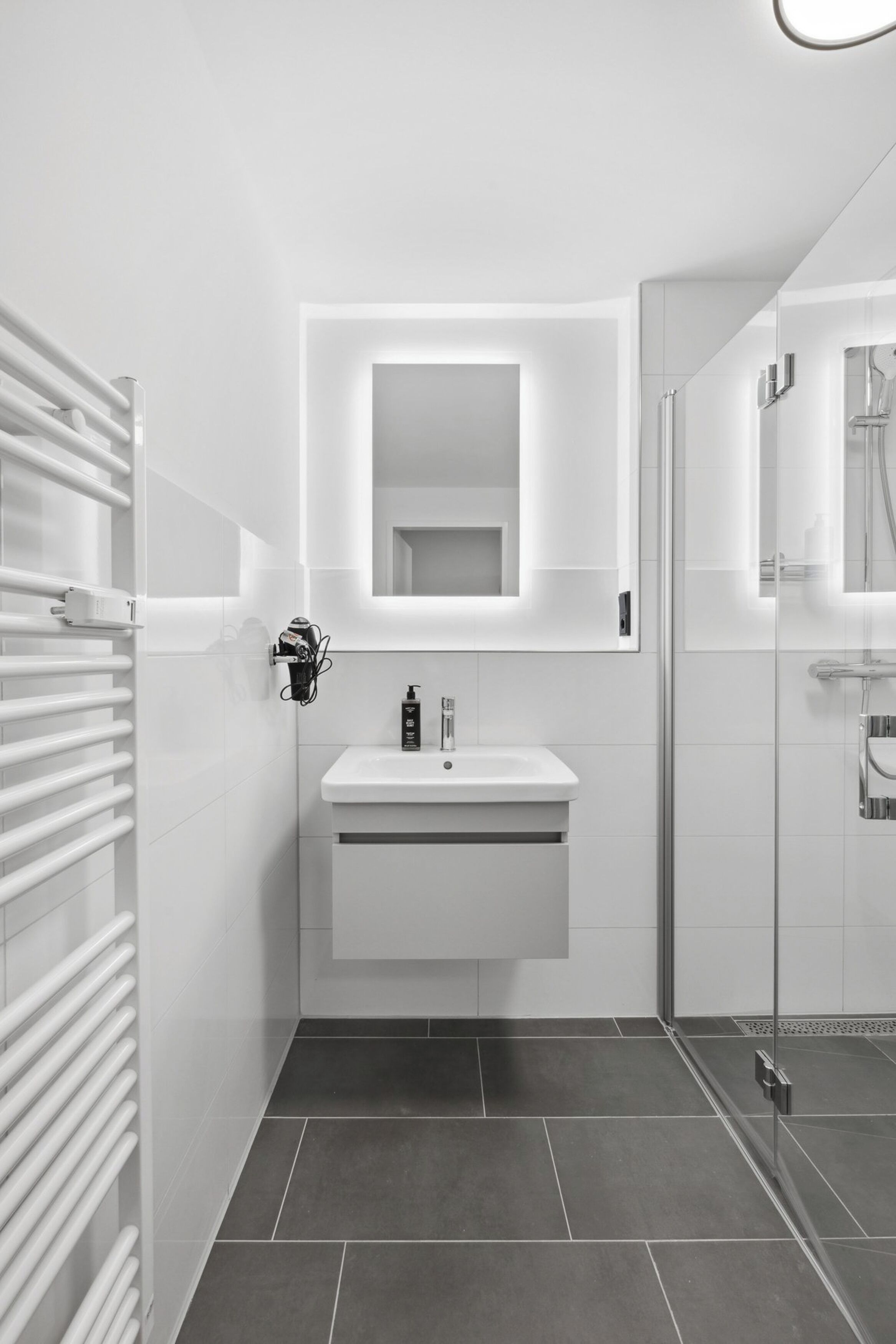 A modern bathroom with a white sink, mirror, and shower.