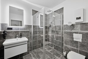 Enjoy a refreshing shower in the bathroom, featuring a glass-enclosed shower with a handheld showerhead and wall-mounted control panel.