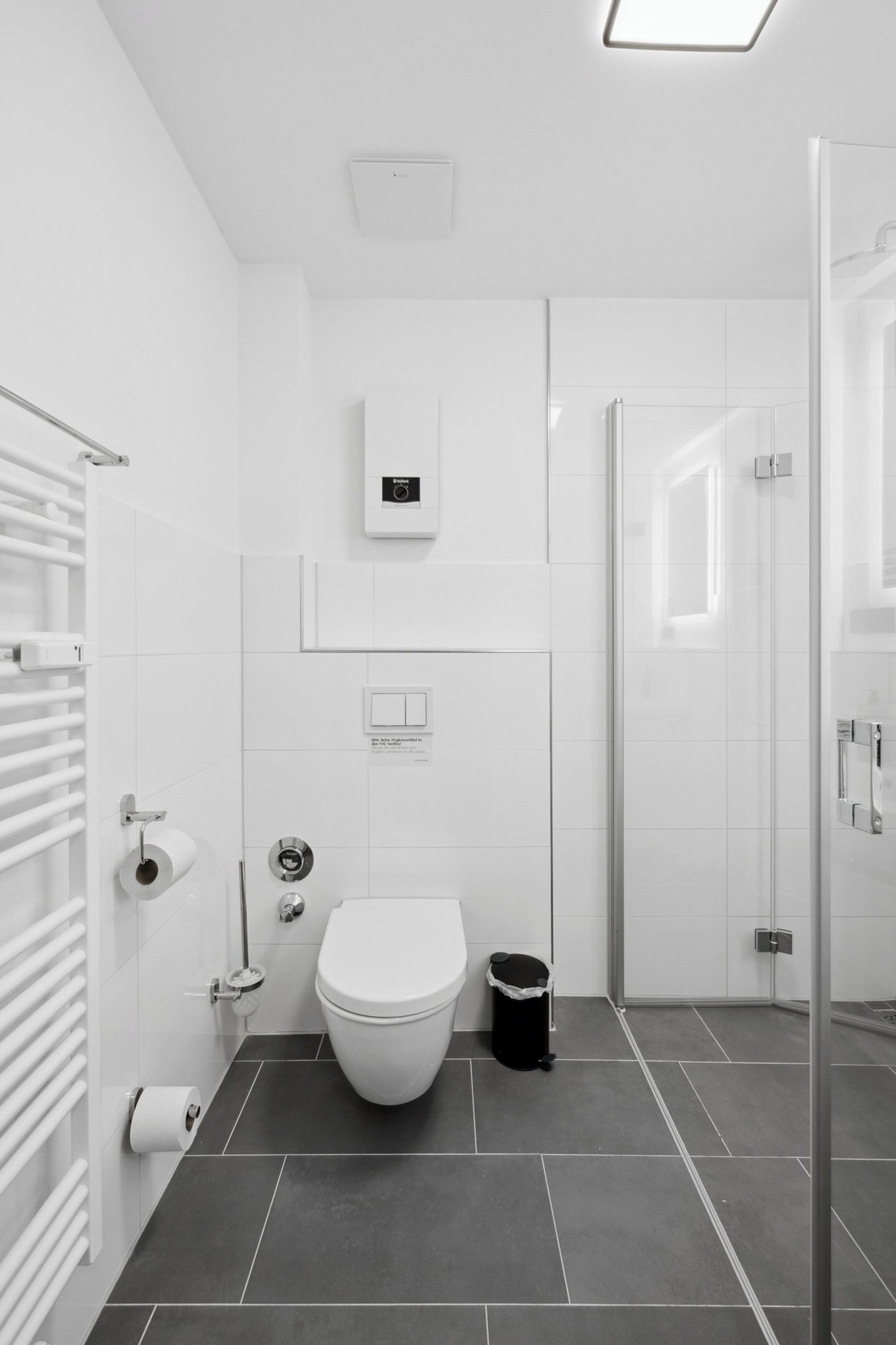 A modern bathroom with a toilet, bidet, and a glass shower enclosure.
